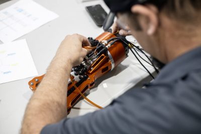 A view over the shoulder of a man testing an electronic device.